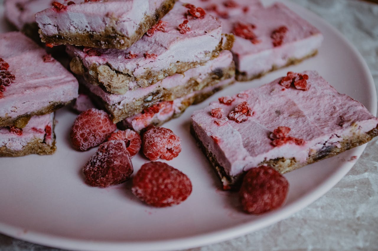 About Close-up of raspberry frozen dessert bars with fresh raspberries.